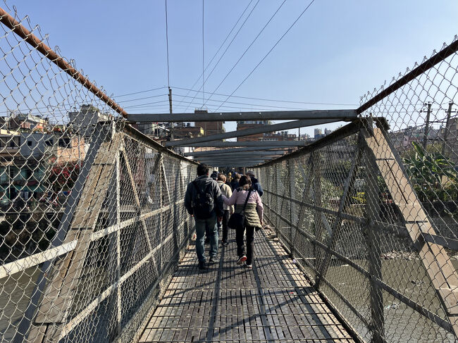 カトマンズ市内観光スタート！<br />ホテルをバスで出発して、ヴィシュヌマティ川の東側でバスを降り、歩行者専用の橋を渡ります。数十年前は泳げる川だったそうですが、今は｡｡｡