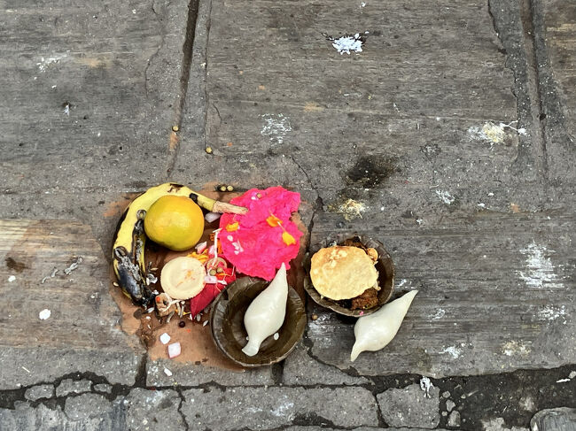 道ばたのお供え物。<br />らっきょうの形をした白いものは、「ヨモリ」というおまんじゅうのようなお供え物だそう。