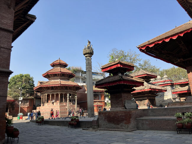 マッラ王の石柱を、ハヌマンの像の前から見る。<br />石柱の左側の八角形の建物は何でしょうね。これまた特徴的なのに。<br />ダルバール広場とその周辺には、観光客には説明されない建築物がいっぱいあります。それらも含めて世界遺産の風景を構築していますね。<br /><br />ダルバール広場への入場チケットには、ハヌマン・ドカの入場料も含まれていますが、時間の関係か、ハヌマン・ドカには入場しませんでした。<br />