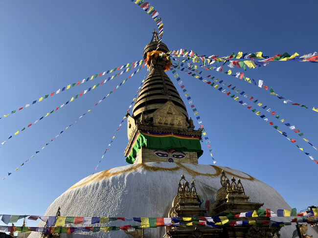 スワヤンブナートは、13世紀にはすでにカトマンズ盆地で重要な仏教の聖地になったとされ、中央には大きなストゥーパがあります。<br />台座の上は半円球のドーム、その上の基部の四面には世界を見渡す仏陀の目が描かれ、鼻にあたるところはネパール数字の「1」となっています。更に上は13層の塔、円形の傘、尖塔と空にそびえ、経文が書かれたタルチョ（五色の旗）が風にたなびくさまは、これまた「ざ・ネパール」の風景の一つ。実際に眼で見ることができてよかったです。