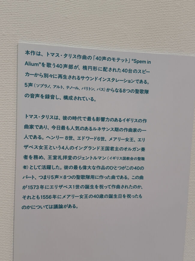 作者紹介のパネルもありました<br />書き起こししておきます<br /><br />「本作は、トマス・タリス作曲の「40声のモテット」“Spem inAlium”を歌う40声部が、楕円形に配された40台のスピーカーから別々に再生されるサウンドインスタレーションである。<br />5声（ソプラノ、アルト、テノール、バリトン、バス）からなる8つの聖歌隊の音声を録音し、構成されている。<br />トマス・タリスは、彼の時代で最も影響力のあるイギリスの作曲家であり、今日最も人気のあるルネサンス期の作曲家の一人である。ヘンリー8世、エドワード6世、メアリー女王、エリザベス女王という4人のイングランド王国君主のオルガン奏者を務め、王室礼拝堂のジェントルマン（イギリス国教会の聖職者）として活躍した。彼の最も偉大な作品のひとつがこの40のパート、つまり5声✕8つの聖歌隊用に作った曲である。この曲が1573年にエリザベス1世の誕生を祝って作曲されたのか、それとも1556年にメアリー女王の40歳の誕生日を祝ったものかについては議論がある。」