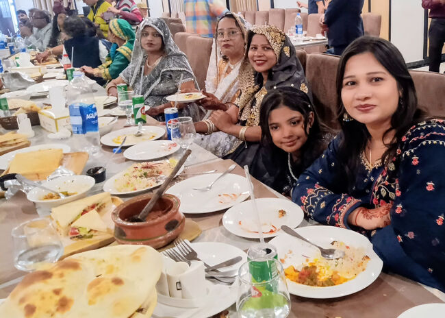 隣りのテーブルでは披露宴ランチ中。<br />女性陣と子供は手前側、男性陣は後方側に座っています。男性リーダ格が写真撮影とSNS掲載OKだからと勧められ、カメラ目線・笑顔表情での1枚となりました。パキスタンはイスラム教のお国ですが、サウジなどに比べたら服装の規律などは割と緩やかな気がします。