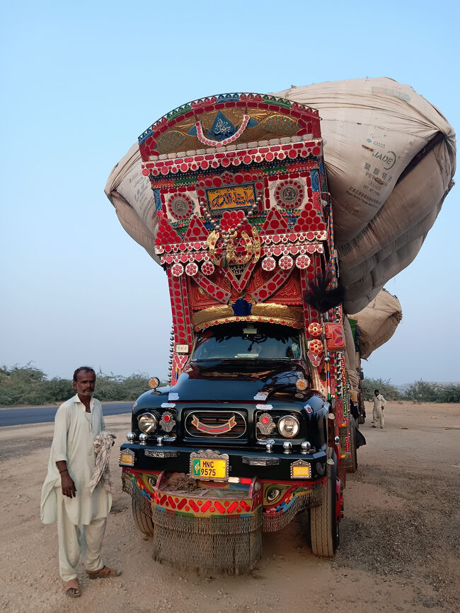 街道沿いの広場でデコトラが停車中なので立ち寄ります。<br />荷台をはみ出して積まれているのは穀物、もみ殻や藁のようで、カラチなどの飼料工場へと運ぶとのこと。<br />