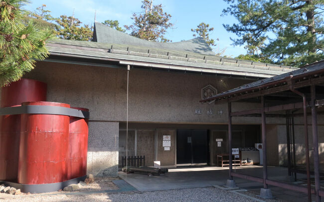 　拝殿横にある神祜殿。出雲大社の宝物殿だ。左側の柱は発掘された古代社殿の柱のモニュメント。この柱が発掘されたことで、オオクニヌシが国譲りの代わりに巨大な社殿を要求したという神話が裏付けられた