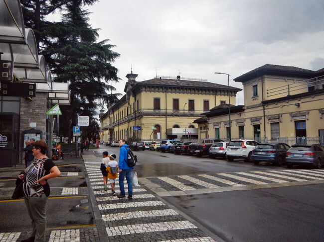 11時10分、ドモドッソラ駅前のバスターミナルの一番駅寄りのプラットフォームに到着。ドライバーのおばちゃんに帰りのバスが出発するプラットフォームや同じ大きさの車が来るのか確認する。｢その日によって車種も出発するプラットフォームは変わるから、ここに来たら上の電光掲示板をよく見てね。｣とアドバイスを受ける。<br />到着したプラットフォームからドモドッソラ駅を望む。中央奥の建物がトレニタリア(旧イタリア国鉄)の駅。右手前が国境警備隊の建物。<br />今日は駅に用はないのだが、周辺にトイレがないので駅の有料トイレを使わざるを得ない。有料トイレは写真の駅の建物と国境警備隊の建物の間を入ったところにある。1人1ユーロ。清潔で快適なトイレだ。