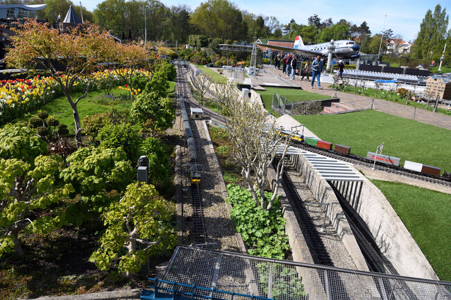 花と緑に囲まれた庭園の中を、模型の列車が走るにぎやかな風景です。