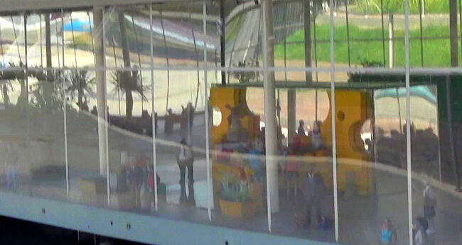 ガラス越しに見えるターミナル内には、色鮮やかな設備と人々の姿があり、空港の中にある遊び場や休憩スペースのような雰囲気が感じられます。