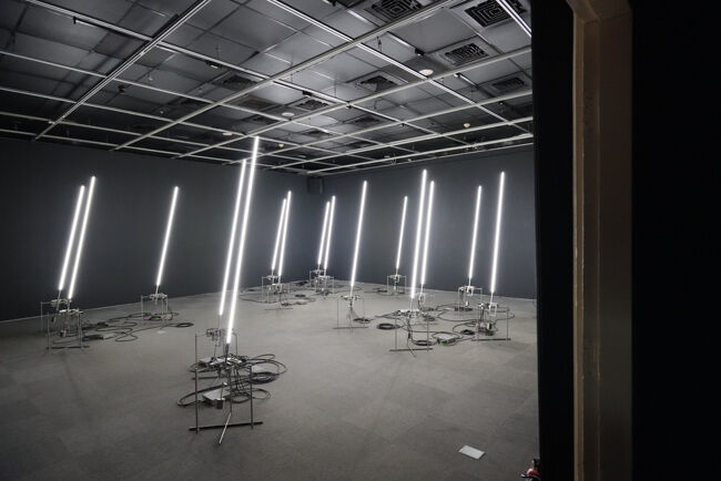 別の部屋。スターウォーズのライトセーバーみたいなのが、規則的に動く作品<br /><br />大きな力に踊らされる市民？とか？