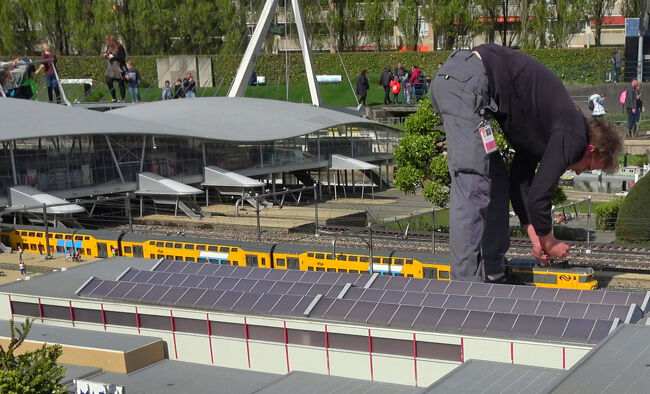 模型の列車に手を加える作業の様子が見られ、展示の裏側まで感じられる場面です。曲線屋根の駅舎や周囲の建物も丁寧に作られていて、交通の風景が生き生きと再現されていました。<br />