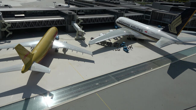 貨物機のDHLと旅客機のシンガポール航空が並ぶ場面で、空港の多様な機能がよく表現されています。