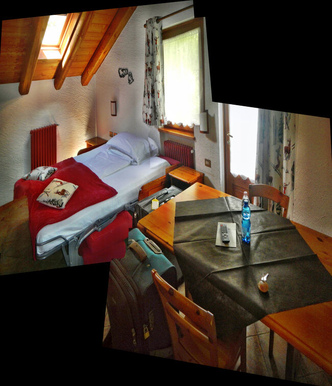 入り口のドアを開けて室内に入ったところ。写真を2枚繋げたら写真が凸凹になってしまった。手前がダイニングテーブルで奥にダブルベッド。典型的なスタディオタイプの部屋だ。ベッドに枕と掛け布団が一組しかセットされていないのは、フロントが1人滞在と間違えたため。15時のチェックイン時に間違いに気づいてすぐにもう一組セットしてくれた。