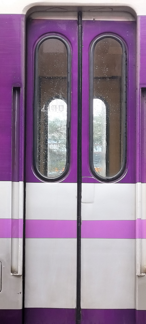 水洗いが終わった車両のドアをよく見ると、ガラス窓の「自動ドア」の文字がひっくり返っていた。<br /><br />日本からやってきた旧国鉄車両かな？