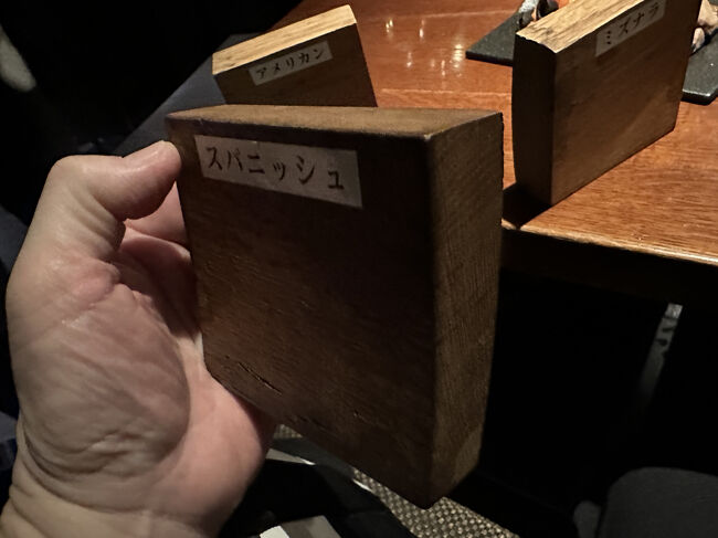 日比谷BAR WHISKY-S・樽材サンプル<br />スパニッシュオーク樽材は、ウイスキーやワインの熟成に用いられる木材の中でも、特にそのユニークな特性とリッチな風味で知られています。スパニッシュオークは主にスペイン北部のガリシア地方で育つ、ヨーロピアンオークの一種です。この木材が樽材として重宝されるのは、以下のような特徴があるからです。<br /><br />・生育環境成長が遅く、木目が粗い傾向があります。 そのため、樽として使える木材がアメリカンホワイトオークに比べて少なく、希少価値が高いです。<br />・高いタンニン含有量 他の主な樽材に比べてタンニンを多く含み、これがウイスキーに深みと複雑さをもたらします。<br />