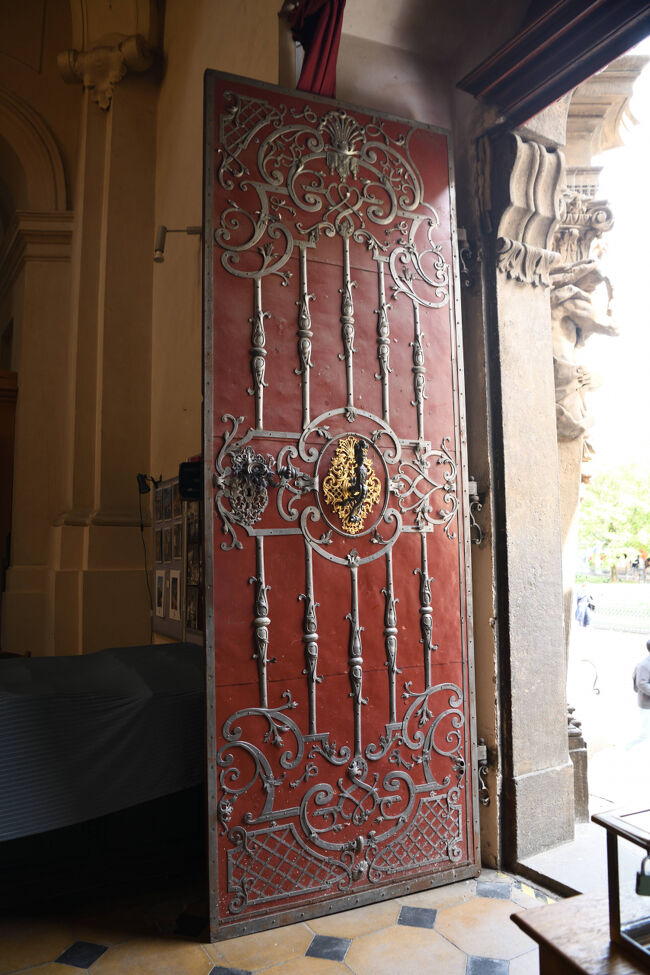 赤い扉の中央に金色のライオンが飾られた重厚な扉。<br /><br />鉄の装飾と石造りの枠から、建物の歴史と格式を感じました。