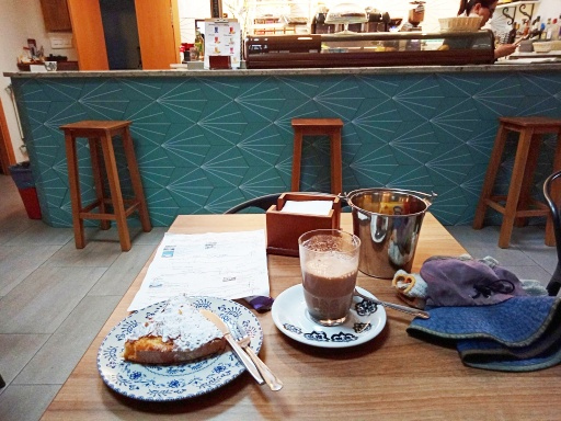 次の村にはバルがあったのでコラカオとサンチャゴケーキで朝飯みたいなことをする。トルティージャやエンパナだとか、もっと実力のある物を食べたいけど、このバルにはこれしか無かった。ケーキでも食べられないよりずっとマシだったけど。<br />ガラスのコップの前に金属の小さいバケツみたいのがありますが、ゴミ入れです。スペインのバルには付き物です。